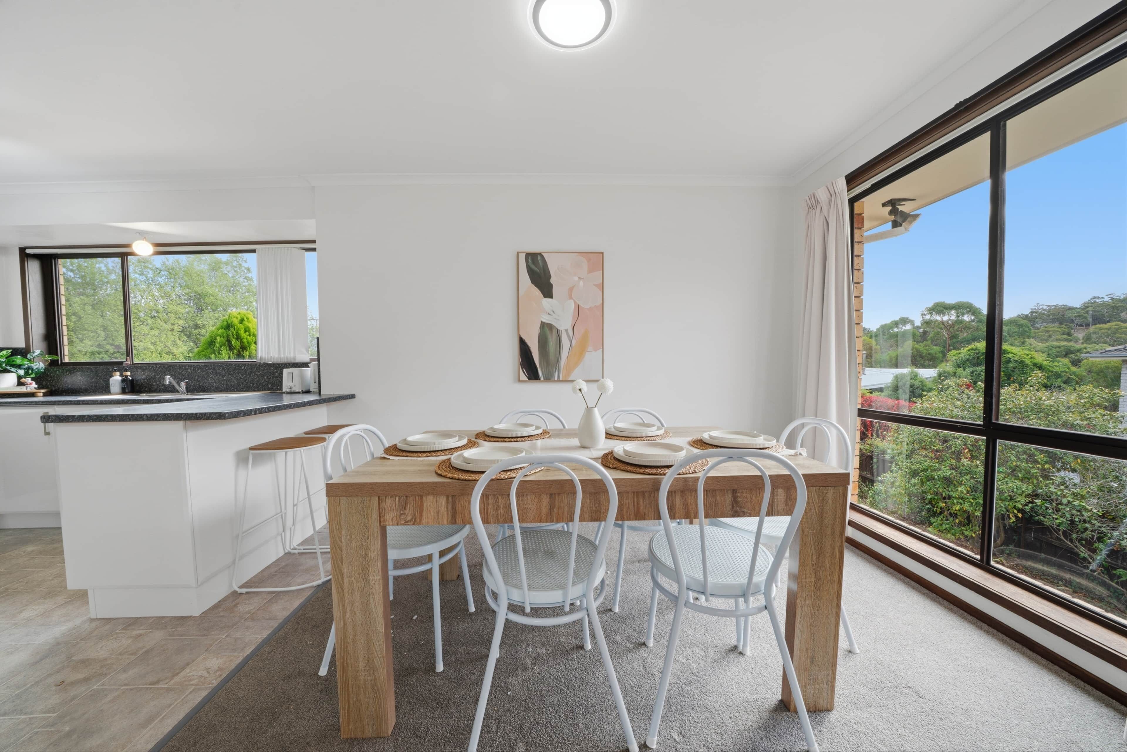 Una cocina moderna con comedor, ventanas amplias y vistas a zonas verdes.