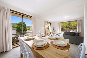 A dining area with a table set for four, a sofa, and a view of the outdoors.