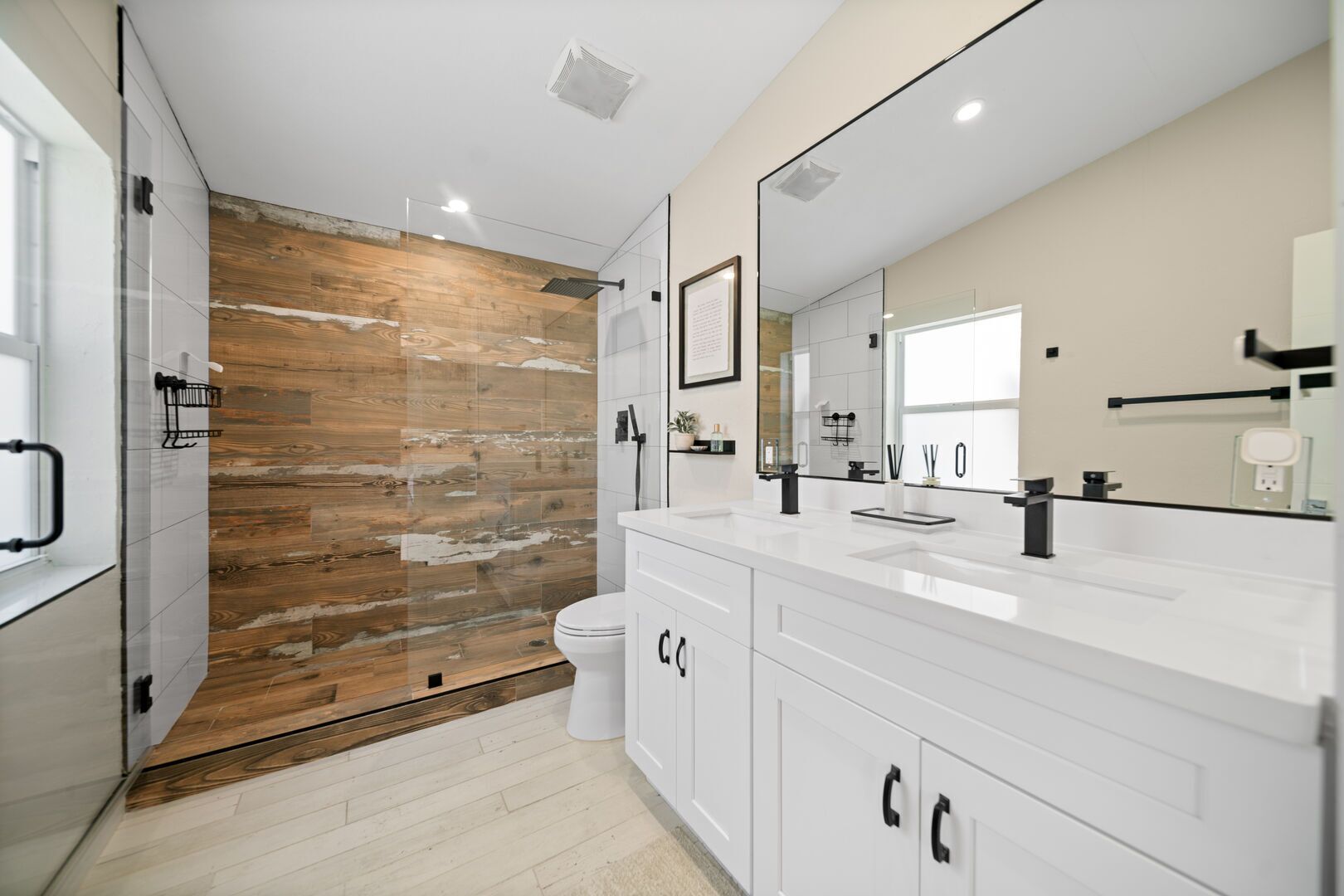 Un bagno moderno con una parete decorata in legno, uno specchio grande e un mobile lavabo bianco.
