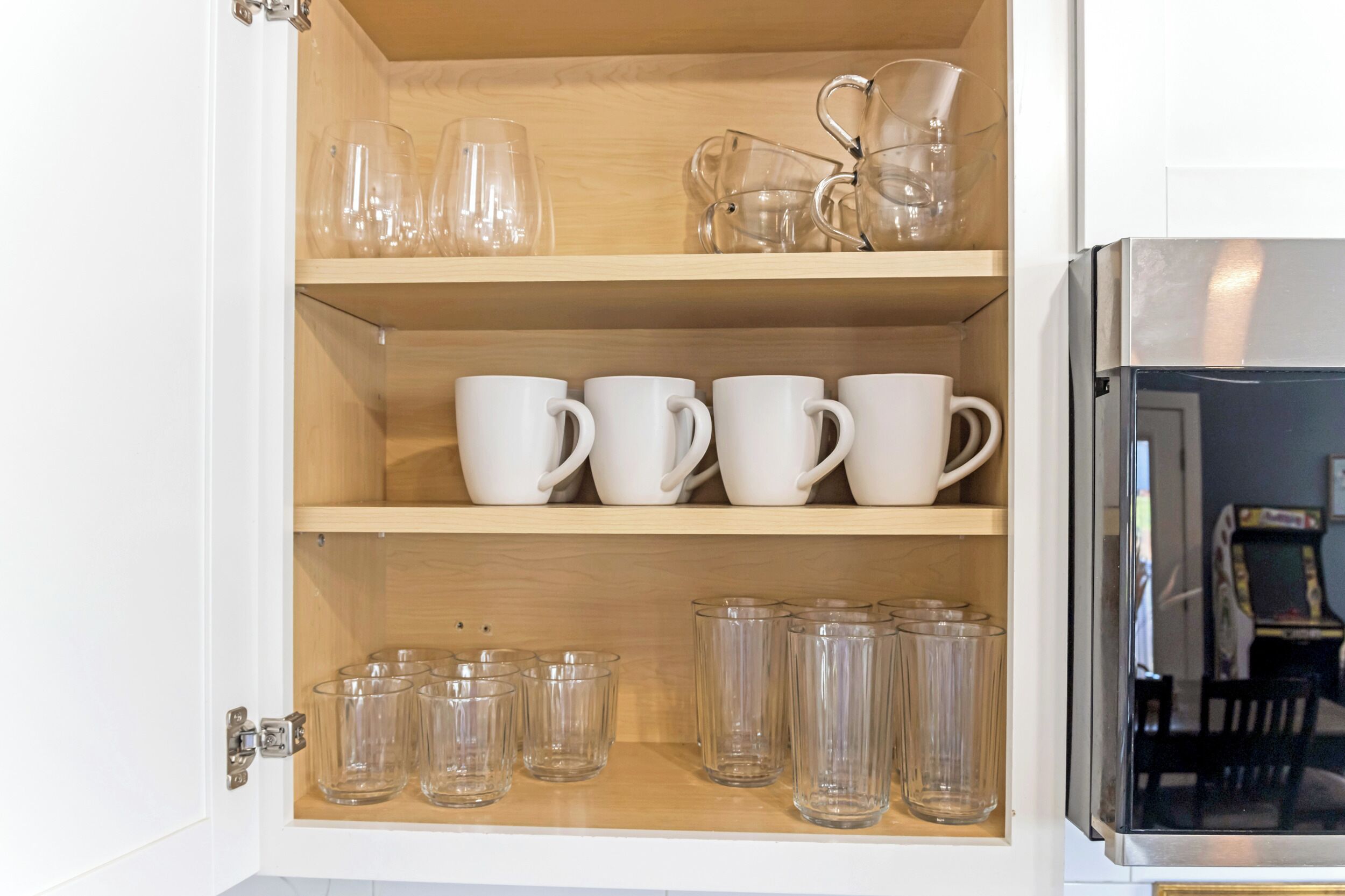 Un meuble avec des étagères contenant divers objets en verre et des tasses.