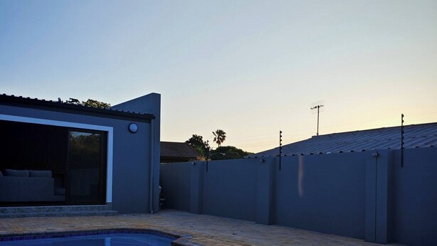 Una piscina con vistas despejadas a los alrededores, incluyendo un edificio con puerta de garaje y un patio cercado.