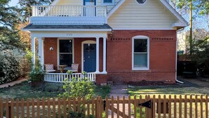 A two-story house with a front porch, a small balcony, and a wooden fence in front. - Downtown Boulder, Walk Everywhere…Bursting with Charm, Character and Comfort. (Boulder)