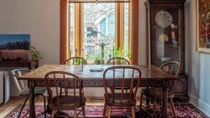 A dining area with a wooden table and chairs, a chandelier, a cabinet with decorative items, and a view of the outdoors. - Downtown Boulder, Walk Everywhere…Bursting with Charm, Character and Comfort. (Boulder)