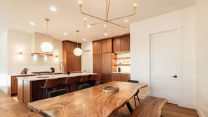 Une cuisine moderne avec des meubles en bois, un grand îlot central et des luminaires suspendus.
