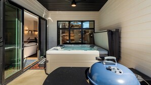 Un espace spa moderne doté d’un jacuzzi, d’un ventilateur de plafond et d’un barbecue.