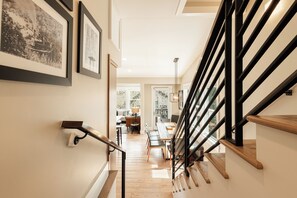 Eine Treppe mit schwarzen Geländern und Holzstufen führt zu einem Essbereich mit Tisch und Stühlen.