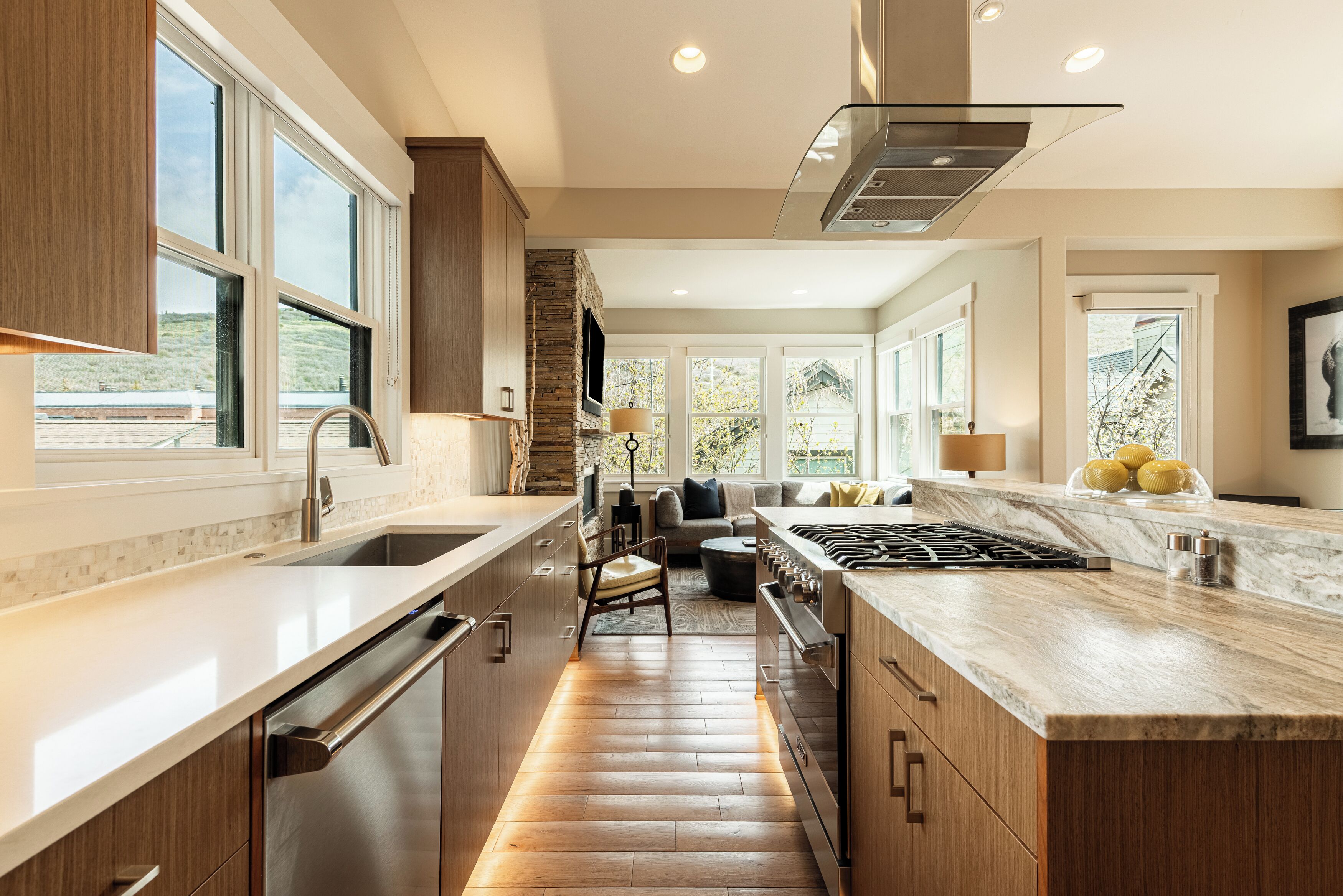 A modern kitchen with a central island, built-in appliances, and large windows.