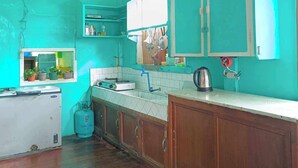 Una cocina con paredes verde azulado, armarios de madera, una estufa a gas y un lavamanos.
