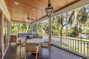 A covered outdoor area with a wooden deck, a round table, and chairs. - Tranquil Waterfront Retreat + Sunrise Views (Bluffton)