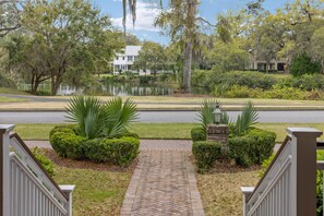 A pathway leading to a house with a pond and lush greenery. - Tranquil Waterfront Retreat + Sunrise Views (Bluffton)