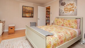 A bedroom with a bed, a bookshelf, a door, and a painting on the wall.