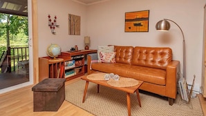 A living room with a leather sofa, a globe, bookshelves, a lamp, and a painting.