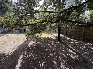 A tree-lined outdoor area with a gravel path, a wooden fence, and a building in the background. - PORNICHET - CHARMANTE PETITE MAISON (PORNICHET)