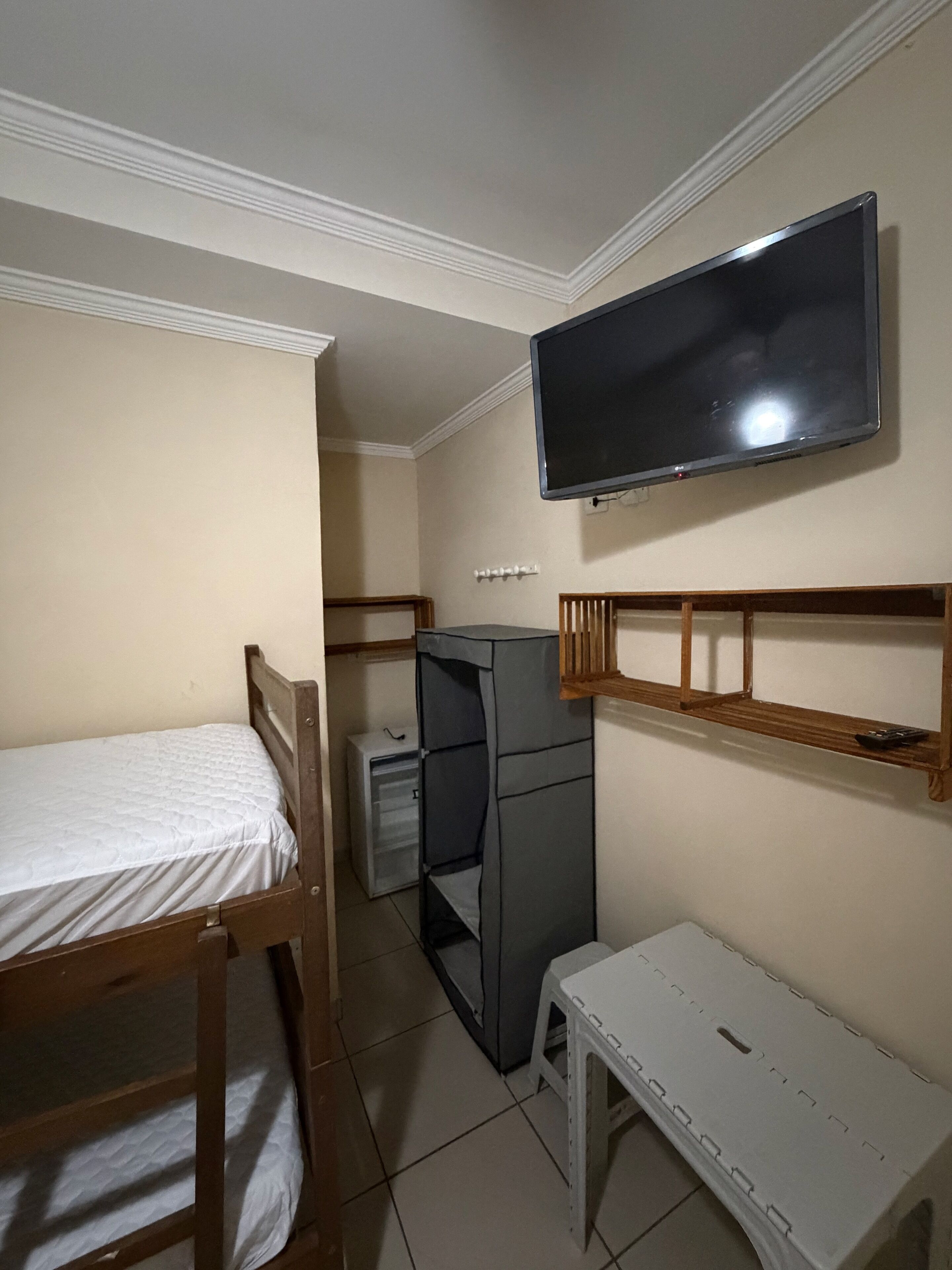 Una habitación con cama, escritorio, televisor y armario.