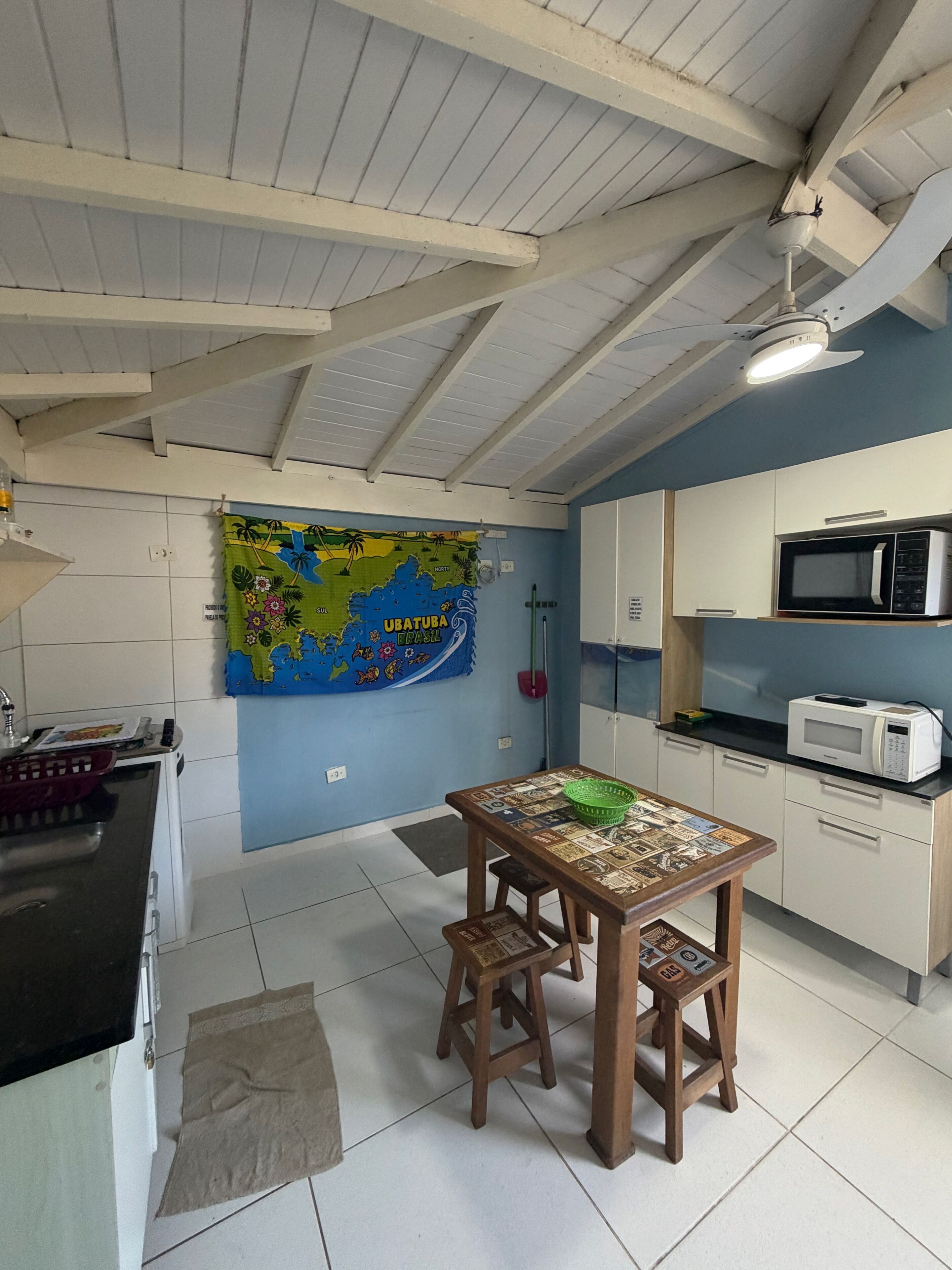 A kitchen with a map, a dining table with chairs, a microwave, and cabinets.
