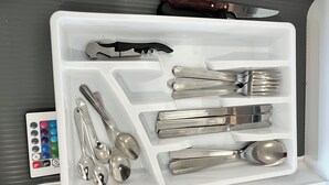 Un cajón con varios utensilios, como cucharas, tenedores y un cuchillo.