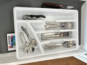 Eine Schublade mit verschiedenen Besteckstücken, darunter Löffel, Gabeln und ein Messer.