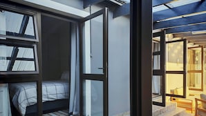 Een kamer met een bed, een raam en een deur die uitkomt op een balkon.