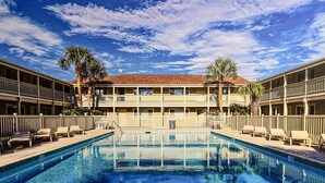 Et hotel med swimmingpool, flere balkoner og palmer.