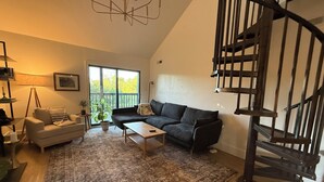 A living room with a sofa, coffee table, and a spiral staircase. - Beautiful and Spacious 4-bedroom home in Lynchburg (Lynchburg)
