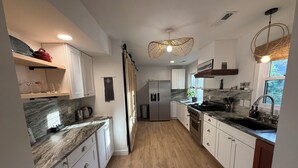 A modern kitchen with white cabinets, a marble countertop, a stainless steel refrigerator, and a wooden floor. - Beautiful and Spacious 4-bedroom home in Lynchburg (Lynchburg)