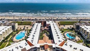 Un hotel con varias piscinas, vistas a la playa y un estacionamiento.