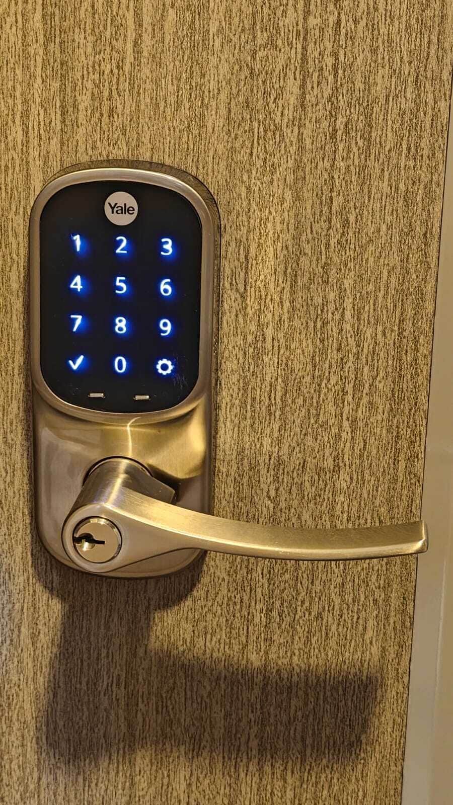 A Yale smart lock on a door with a textured surface.