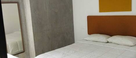 A modern hotel room with a bed, a desk, and a chair.