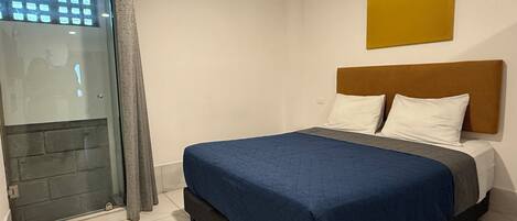 Un dormitorio con cama, cabecera, ventana con cortinas y una obra de arte colgada en la pared.