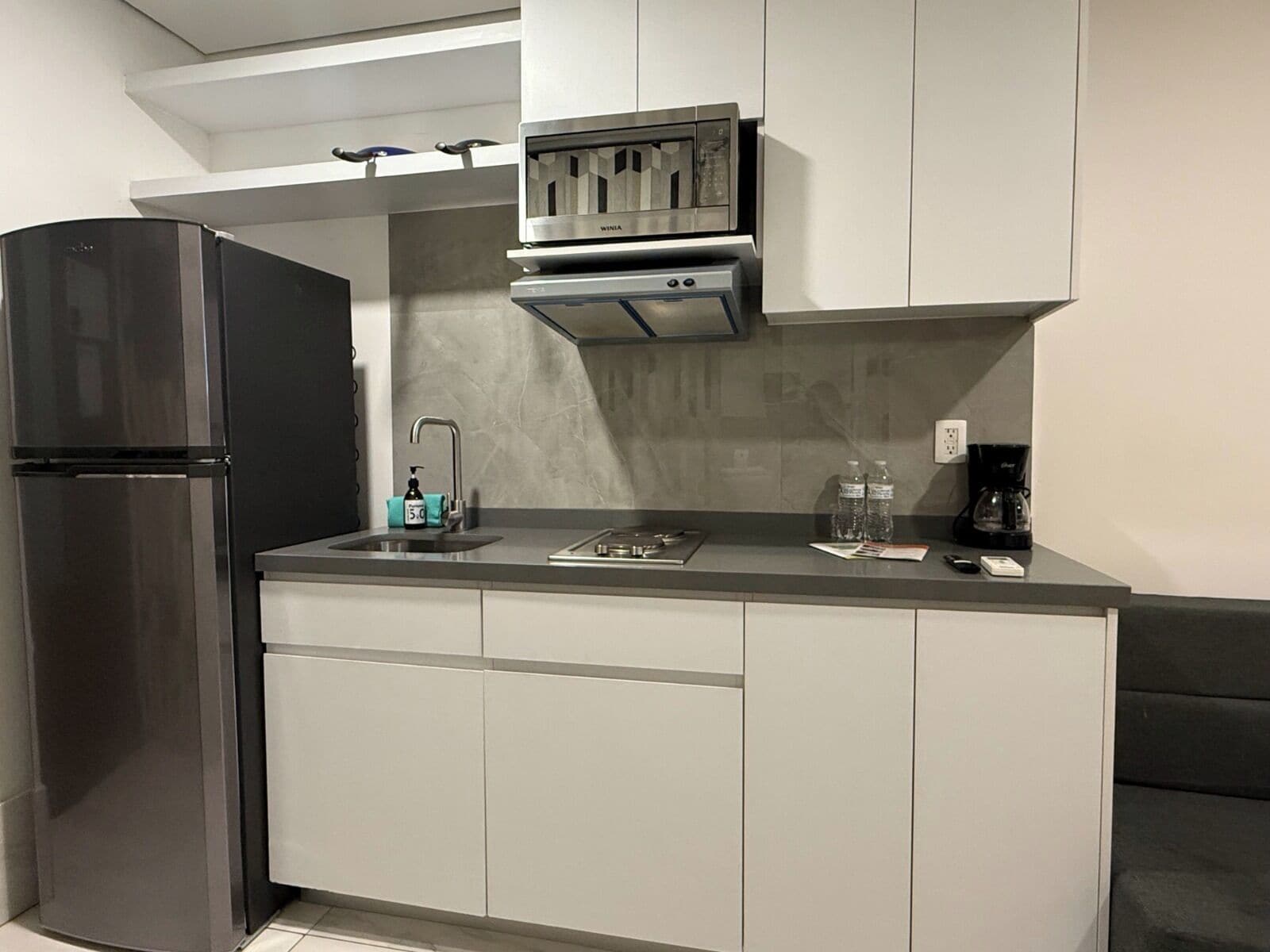 Una cocina moderna con horno empotrado, microondas y cafetera sobre la encimera.