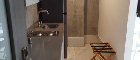 A compact kitchen with a built-in oven, a sink, and a small drying rack.
