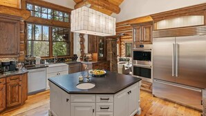 Una cocina amplia con una isla grande, armarios de madera y un refrigerador de acero inoxidable.