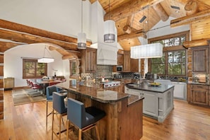 A spacious kitchen with wooden beams, a large island, and bar stools.