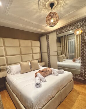 Une chambre d’hôtel avec un grand lit, une tête de lit, une table de chevet, un miroir et un luminaire suspendu.