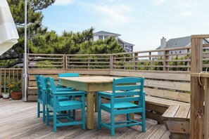 An outdoor wooden deck with a table and chairs, surrounded by a wooden fence and trees. - Thistle: Semi-Oceanfront home in Duck, Elevator, Sanderling Community Amenities (Duck)
