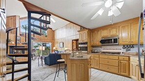 A spacious kitchen with wooden cabinets, a central island, and a ceiling fan. - Thistle: Semi-Oceanfront home in Duck, Elevator, Sanderling Community Amenities (Duck)