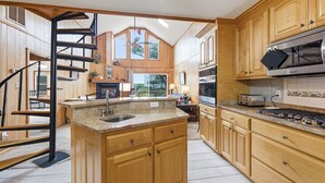 A kitchen with wooden cabinets, a granite countertop, a built-in oven, and a stainless steel range hood. - Thistle: Semi-Oceanfront home in Duck, Elevator, Sanderling Community Amenities (Duck)