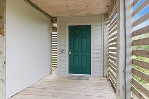 A wooden porch with a green door, a white wall, and a wooden railing. - Thistle: Semi-Oceanfront home in Duck, Elevator, Sanderling Community Amenities (Duck)