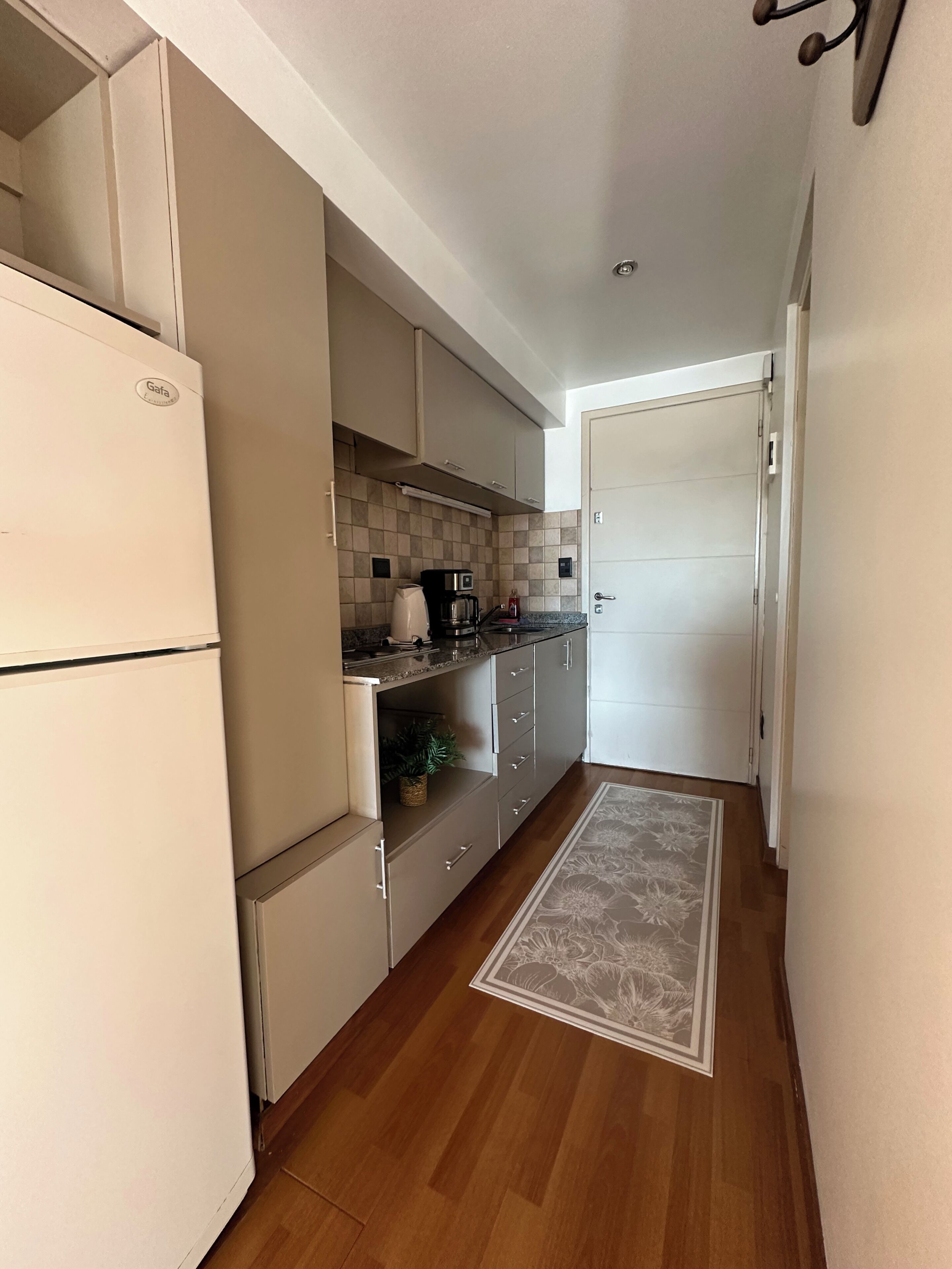 A compact kitchen with a refrigerator, microwave, and coffee maker.