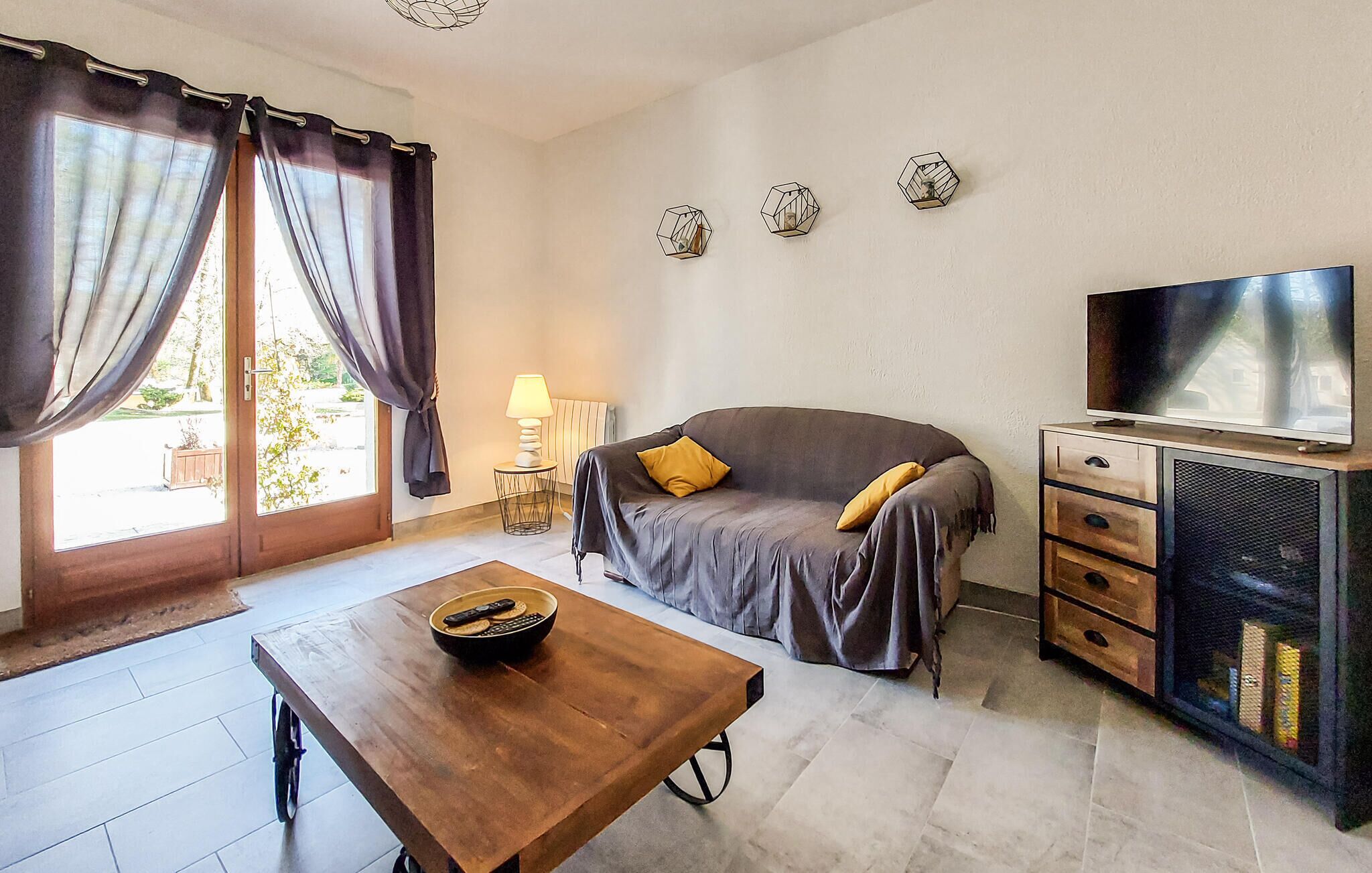 A room with a sofa, a TV, a wooden table, and a lamp.