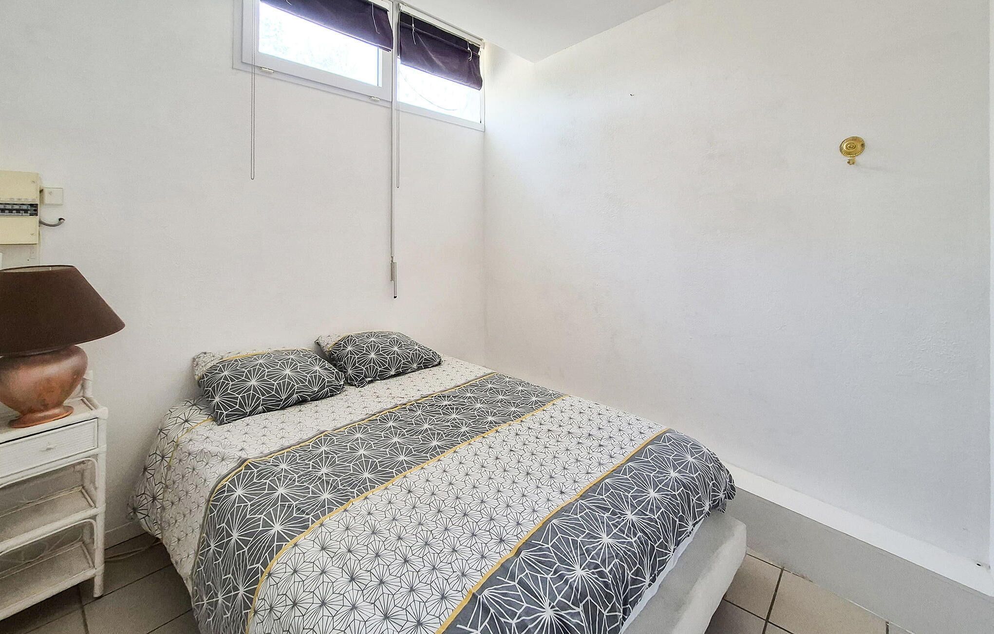 A bedroom with a bed, a nightstand, a lamp, and a window with curtains.
