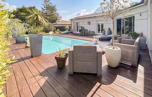 A wooden deck with a pool, wicker furniture, and potted plants. - Cozy home in Tarnès with sauna (Tarnès)