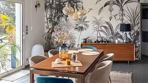 Comedor con una mesa de madera, sillas y un mural decorativo.
