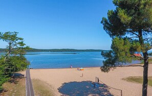 Une plage offrant une vue dégagée sur l’eau, avec quelques personnes et une côte lointaine.