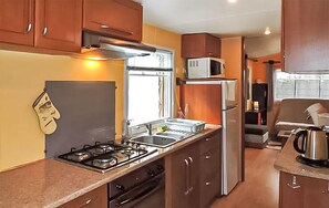A compact kitchen with a gas stove, microwave, refrigerator, and a window. - Awesome (sta)caravan in Sainte-Eulalie-en-Born (Sainte-Eulalie-en-Born)
