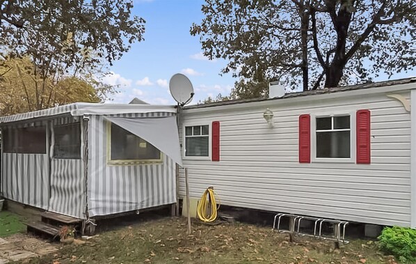 Une maison mobile équipée d’une antenne parabolique, d’un porche couvert et d’un espace jardin.