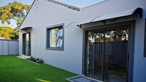 Ein modernes Haus mit gepflegtem Rasen, einem großen Schiebeglastür und einem kleinen Fenster.