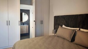 Ein Schlafzimmer mit Bett, Nachttisch, Spiegel und Kleiderschrank.