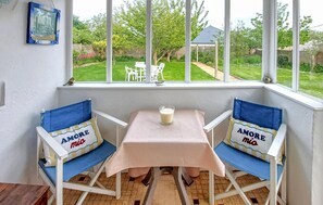 A cozy corner with two blue chairs, a small table, and a window with a view of a garden. - 1 bedroom nice apartment in Pleubian (Pleubian)