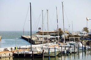 A marina with boats docked, a pier, and a building with a flag.